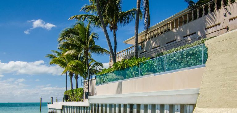 glass pool fence on the edge of a walkway overlooking the ocean.