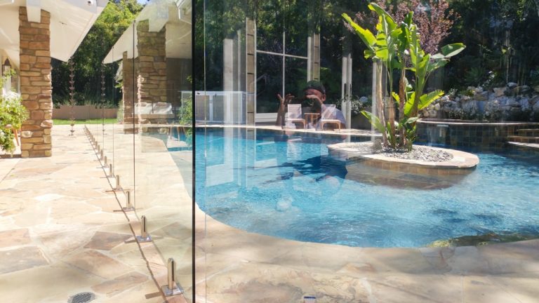 glass pool fence surrounding a swimming pool in a backyard patio.