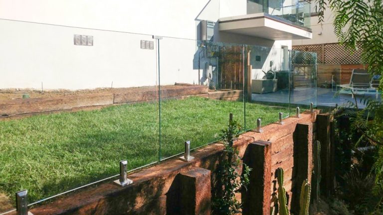 Glass railing in a backyard mounted to wood
