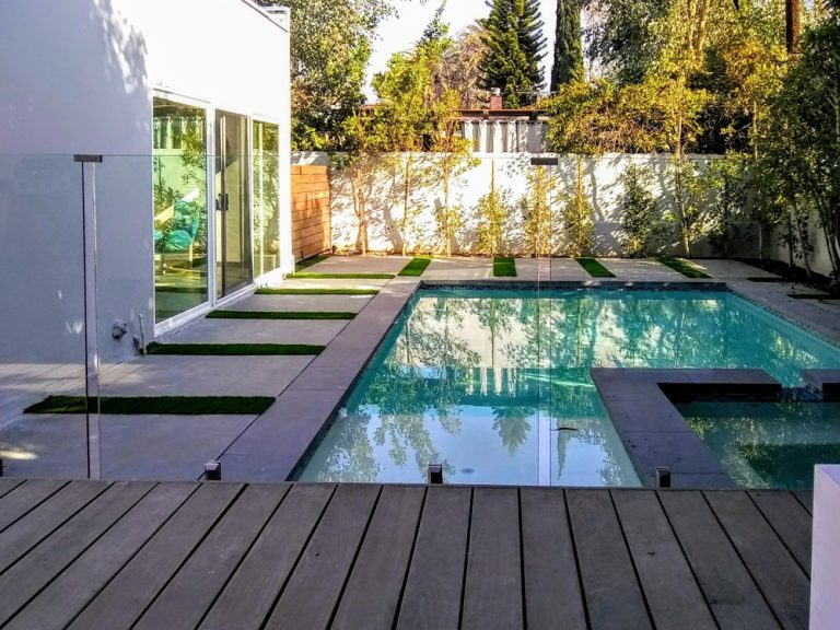 Glass pool fence surrounding a small swimming pool in a backyard