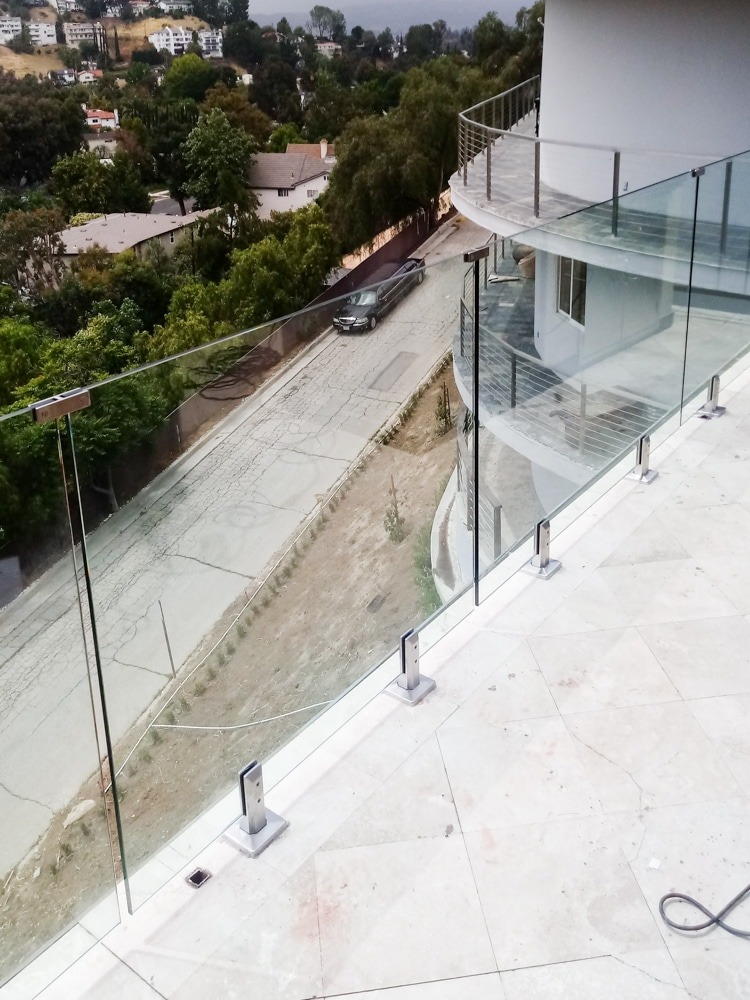 Frameless glass railing at the top of a three-story balcony.