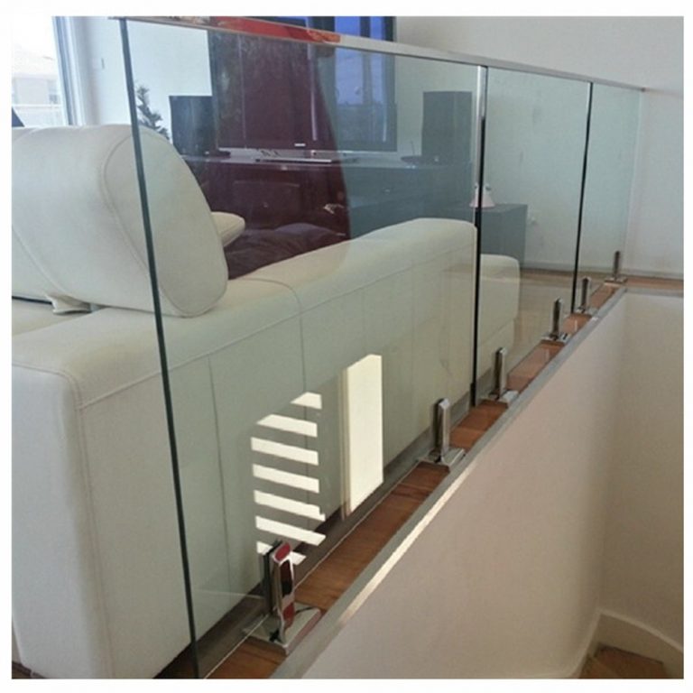 Glass railing inside a home in front of a couch and stairs