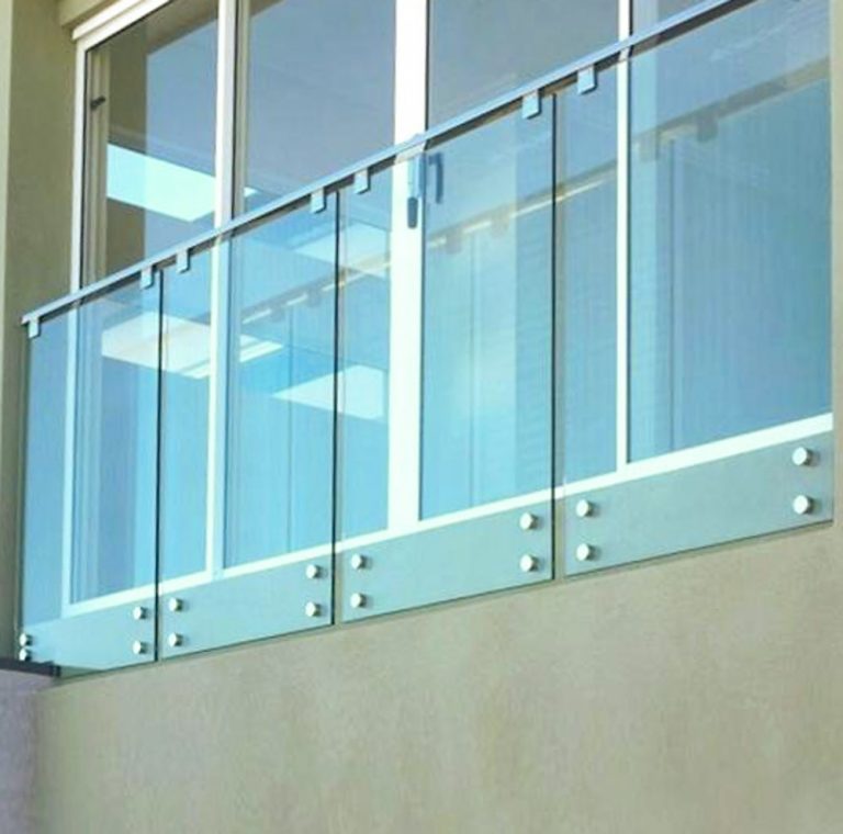 Glass railing mounted to the side of a home in front of windows