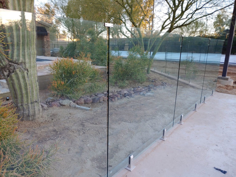 Long frameless glass railing surrounding a back yard