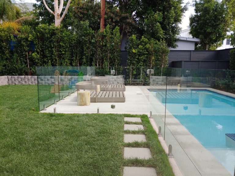 Glass pool fencing in a backyard surrounding a swimming pool