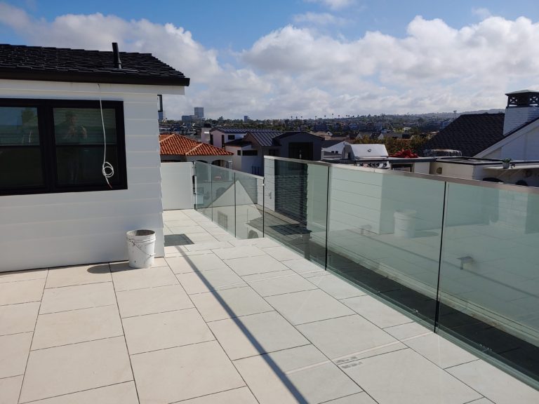 Glass railing with a top cap rail on an outdoor second story balcony connected to a house