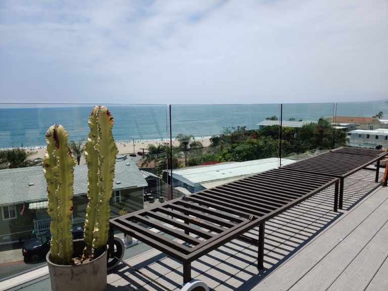 Glass railing on a rooftop deck overlooking the beach