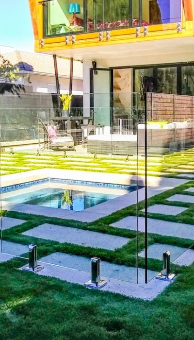 Frameless glass pool fencing surrounding a large pool in a residential back yard